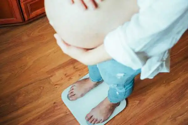 Image of woman weighing herself and experiencing weight gain through pregnancy York